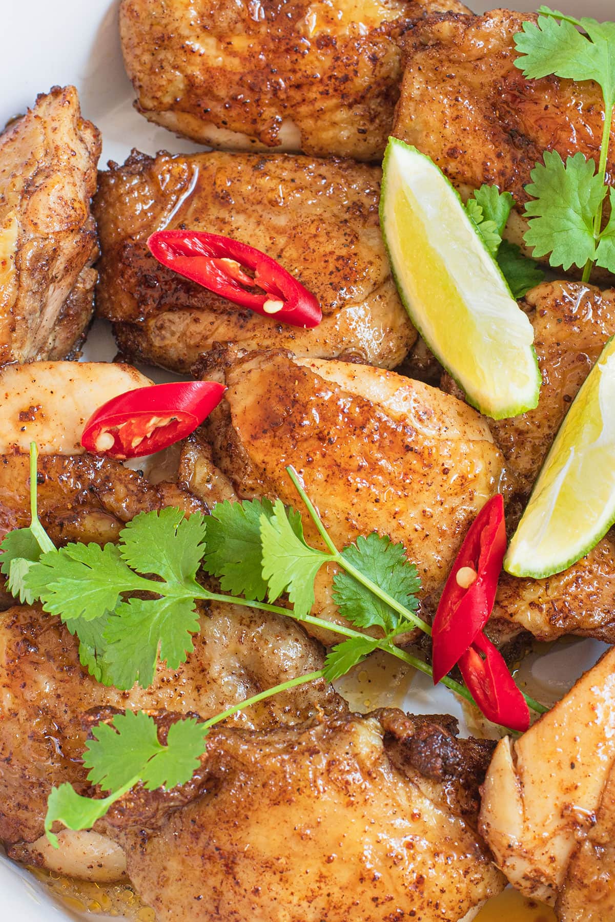 Enticing chicken marinated in flavorful blend of spices with chili slices, lime wedges, and parsley on top. 